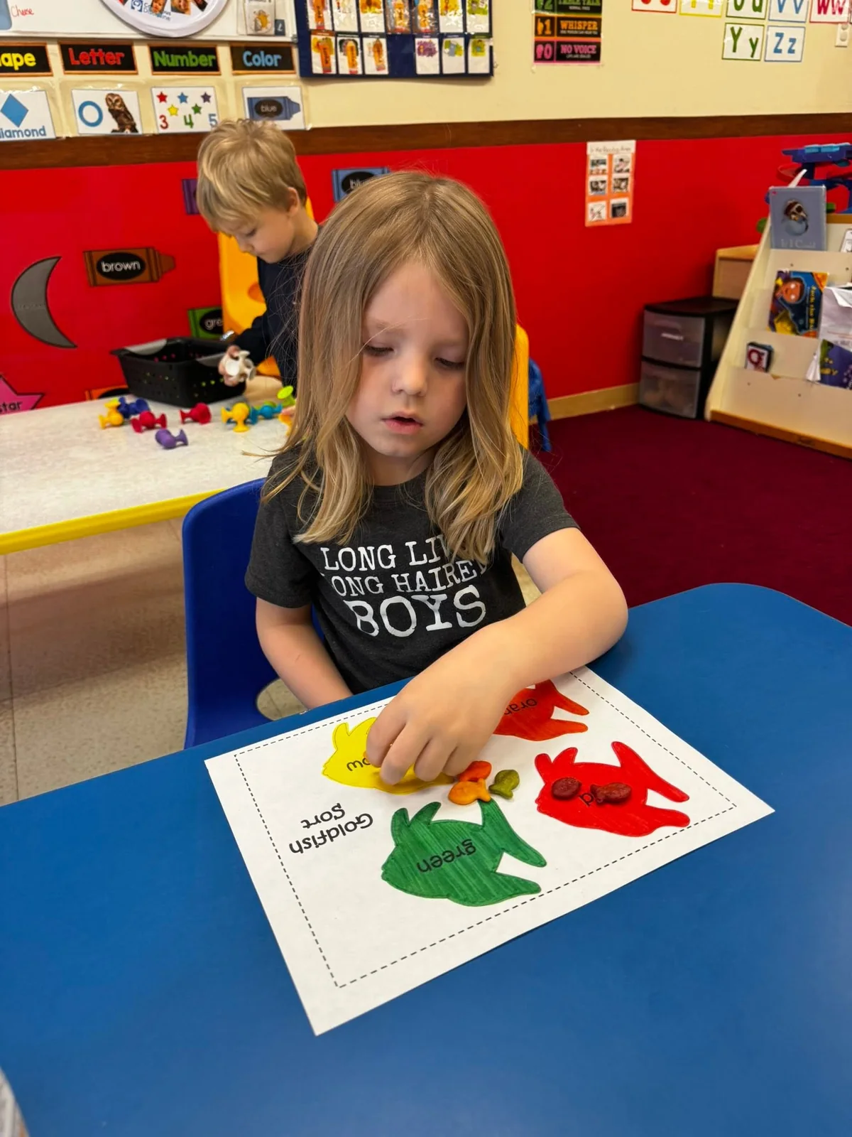 A child making colorful handprints on paper in a Northland classroom