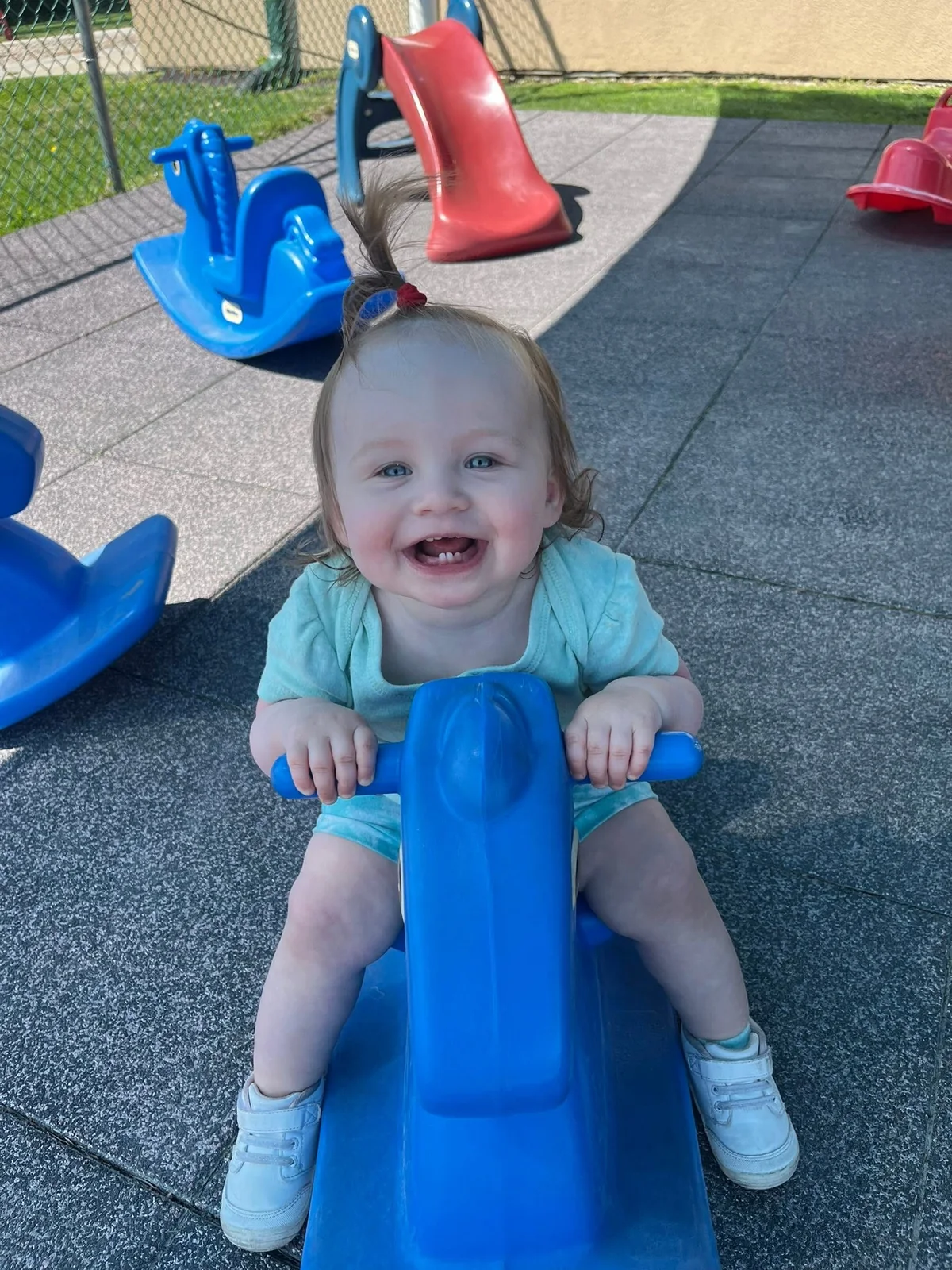 A young child enjoying a blue playground rocker at Northland