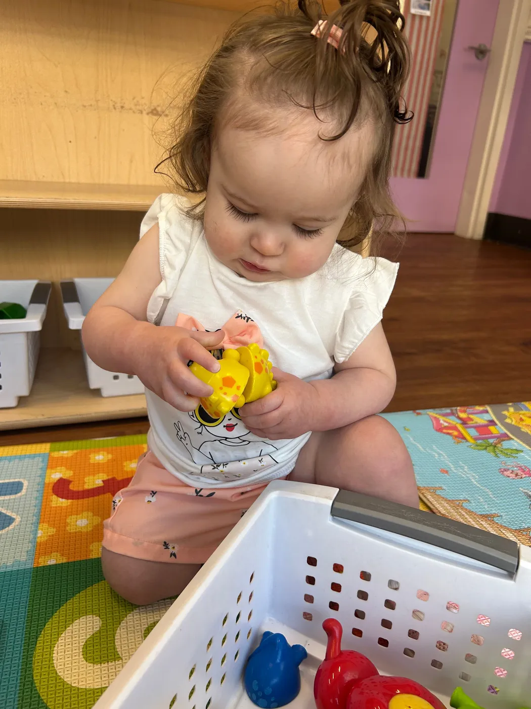 A toddler examining a yellow toy from a basket