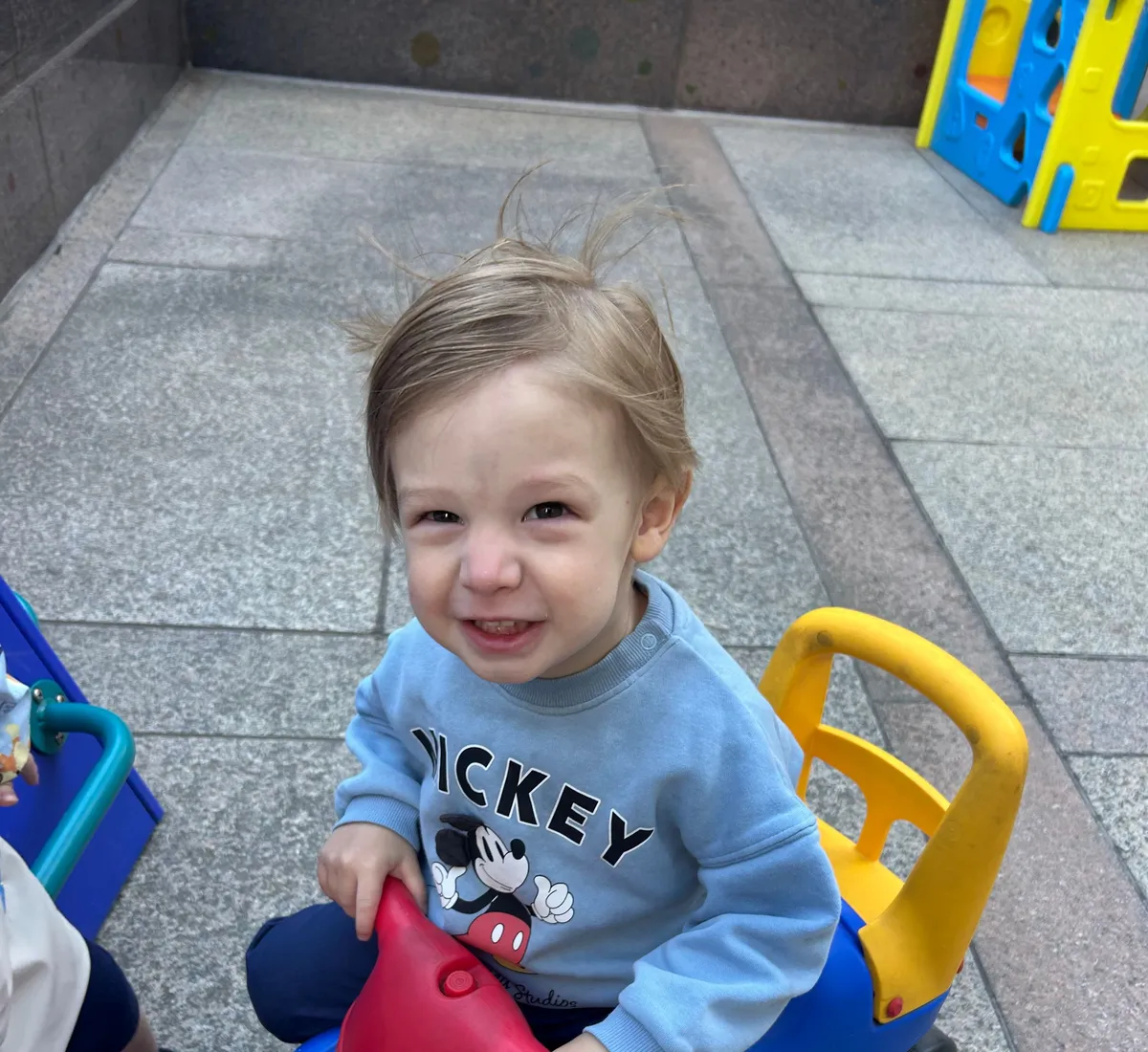 A toddler grinning on a ride-on car